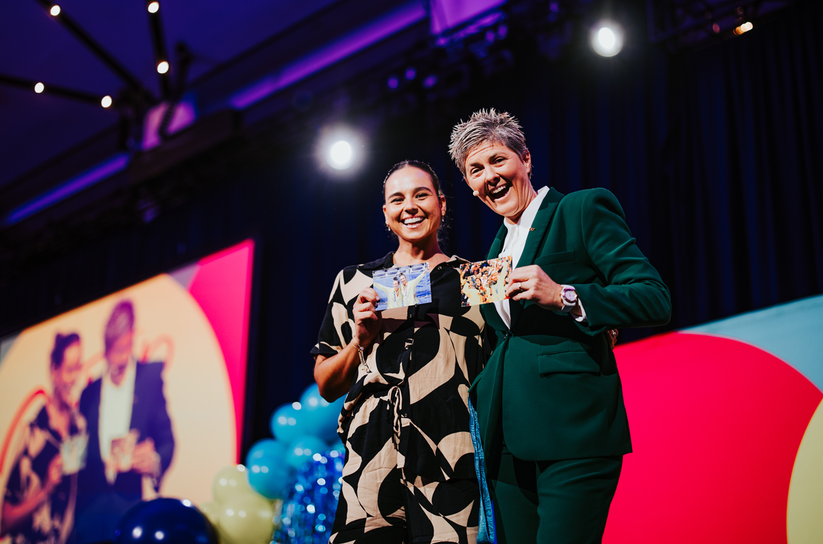 Mariafe Artacho del Solar and Natalie Cook OAM OLY smiling, posing with postcards that each show the other winning an Olympic medal